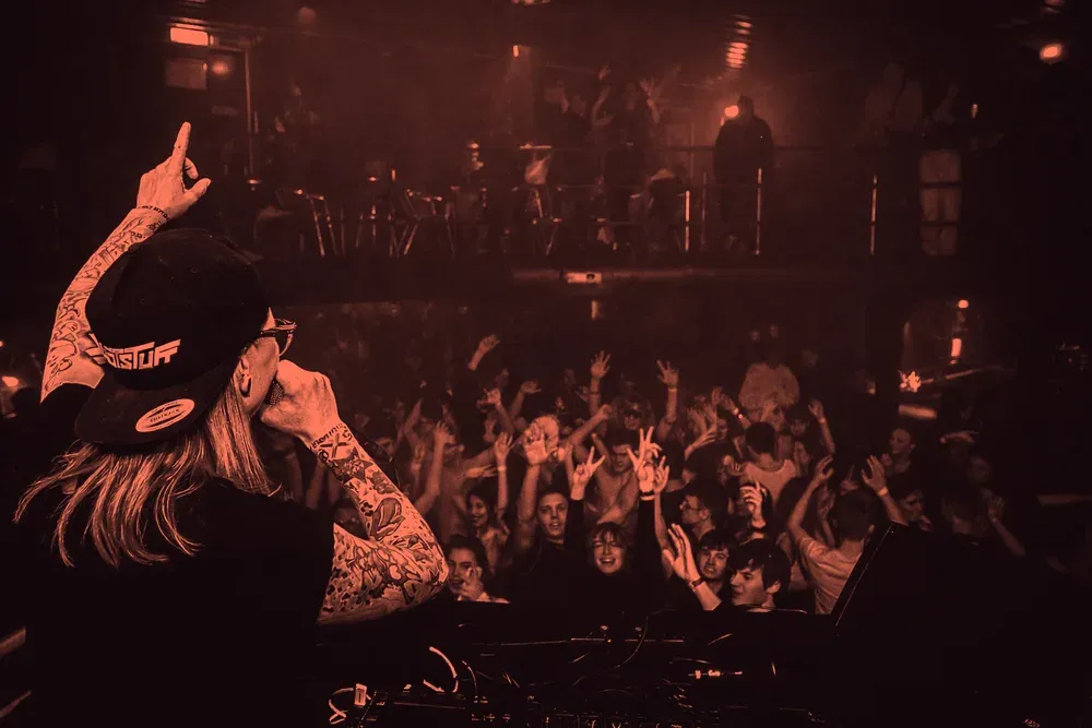 Blick aus der DJ-Booth in eine volle, rot ausgeleuchtete Clubnacht